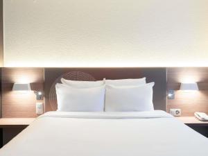 a bed with white pillows in a hotel room at Novotel Suites Genève Aéroport in Geneva +107 photos