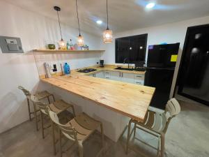 a kitchen with a wooden counter with chairs and a refrigerator at Suerte Bella in San Carlos +2 photos