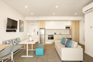 a living room with a couch and a table and a kitchen at Quest Scarborough in Perth +23 photos