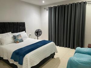 a bedroom with a large bed and a chair at Victoria Falls Accomodation in Victoria Falls