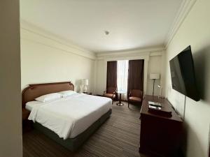 a hotel room with a bed and a flat screen tv at The Imperial Hotel & Convention Centre Korat in Nakhon Ratchasima