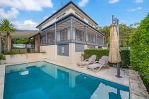 a house with a swimming pool and an umbrella at 15 Derby Road Moffat Beach in Caloundra
