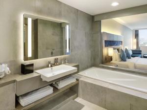a bathroom with a tub and a sink and a bed at Novotel Jakarta Mangga Dua Square in Jakarta +82 photos