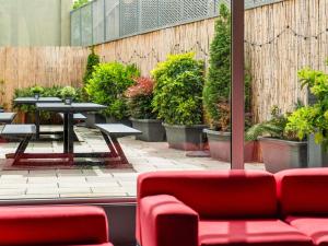 a patio with a table and benches and potted plants at Ibis Barcelona Plaza Glòries 22@ in Barcelona