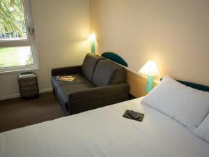 a hotel room with a bed and a couch at ibis Perpignan Nord Rivesaltes in Rivesaltes +140 photos