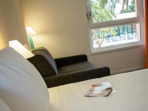 a living room with a couch and a window at ibis Perpignan Nord Rivesaltes in Rivesaltes