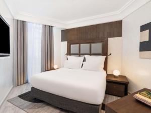 a bedroom with a large white bed and a desk at Zamzam Pullman Makkah in Mecca +109 photos