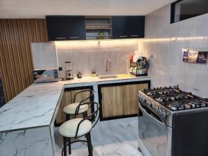 a kitchen with a stove and two chairs in it at Departamento Confortable in Latacunga