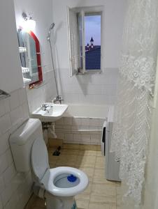 a bathroom with a toilet and a sink and a window at Apartament in Fălticeni