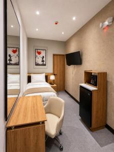 a hotel room with a bed and a desk and a television at Hotel Arkam in San Salvador