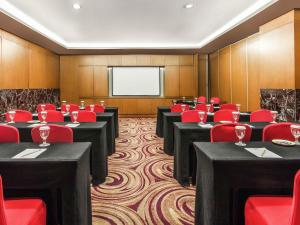 a conference room with tables and red chairs and a screen at ibis Semarang Simpang Lima in Semarang