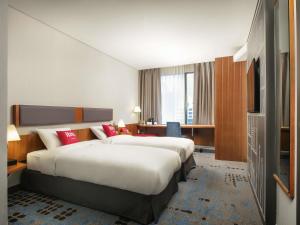 a hotel room with two beds and a television at Ibis Ambassador Myeongdong in Seoul