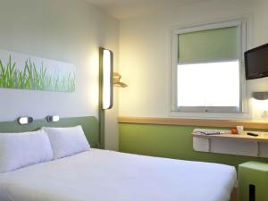 a bedroom with a white bed and a window at Ibis Budget Málaga Centro in Málaga