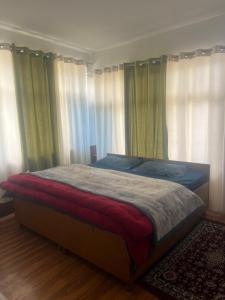 a bed in a bedroom with windows with curtains at Bittu Homestay in Kaza