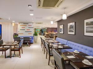 a dining room with tables and chairs in a restaurant at Novotel RJ Santos Dumont in Rio de Janeiro