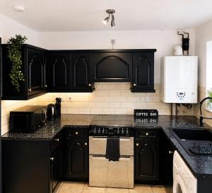 a kitchen with black cabinets and a stove top oven at House in Manchester MVS Snug Urban Hideaway in Manchester
