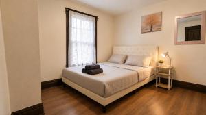 a bedroom with a white bed and a window at Charming 3 Bdr Home 8 mins from the Falls in Niagara Falls