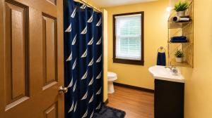 a bathroom with a blue shower curtain with a toilet and a sink at Charming 3 Bdr Home 8 mins from the Falls in Niagara Falls +10 photos
