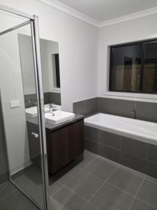 a bathroom with a tub and a sink and a mirror at 11 Lomond street in Beveridge +44 photos