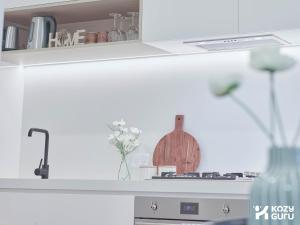 a kitchen with a counter top with a stove and a vase at KozyGuru | Box Hill | Chic & Close to It All in Box Hill
