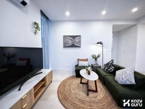 a living room with a green couch and a table at KozyGuru | Box Hill | Chic & Close to It All in Box Hill
