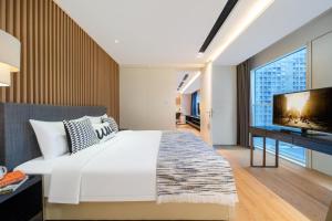 a bedroom with a large white bed and a flat screen tv at Citadines South Chengdu in Chengdu