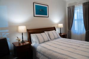 a bedroom with a bed and two lamps and a window at Heritage On Horseshoe Guest House in South West Rocks