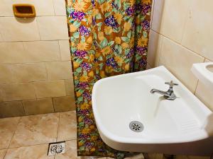a white sink in a bathroom with a shower curtain at LOLI Guest House Iguazú Habitaciones privadas con baño in Puerto Iguazú +65 photos