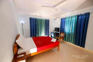 a bedroom with a red and white bed and blue curtains at Venice Castle in Alleppey