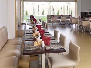 a dining room with long tables and white chairs at Ibis San Luis Potosi in San Luis Potosí