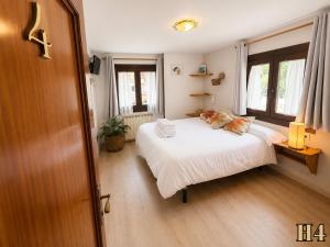 a bedroom with a white bed and a window at Hostal Rural Sant Climent - Habitacions i Apartaments in Taüll