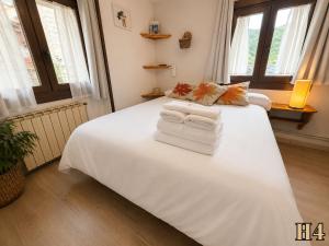 a bedroom with a large white bed with towels on it at Hostal Rural Sant Climent - Habitacions i Apartaments in Taüll