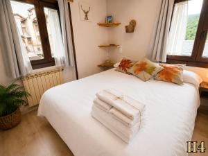 a bedroom with a white bed with towels on it at Hostal Rural Sant Climent - Habitacions i Apartaments in Taüll