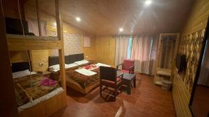 a room with two bunk beds and a table and chairs at The River Edge in Pahalgām