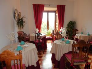 a dining room with tables and chairs with red curtains at Hostal Puerta Medina in Sigüenza