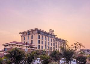 a hotel building with palm trees in the foreground at Soaltee Westend Premier in Nepālganj