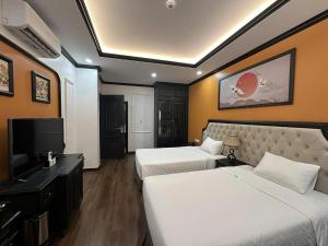 a hotel room with two beds and a flat screen tv at Moma Paris Hotel Ninh Bình in Ninh Binh