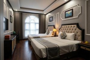 a hotel room with two beds and a television at Moma Paris Hotel Ninh Bình in Ninh Binh