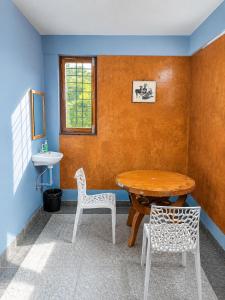 a room with a table and two chairs and a sink at Avora Auroville in Auroville