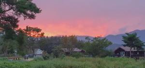 a sunset over a field with houses and trees at Morning Sound in Pyeongchang +10 photos