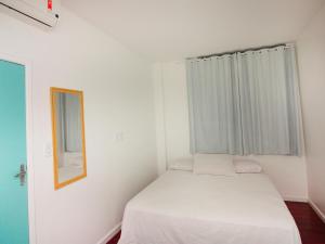 Un pequeño dormitorio con una cama blanca y una ventana en El Misti Suites Copacabana, en Río de Janeiro