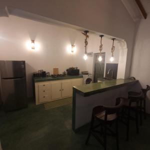 a kitchen with a counter and some chairs and a refrigerator at Shells By D in Negombo
