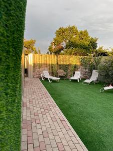 a garden with two white chairs and a fence at Волна in Balqash
