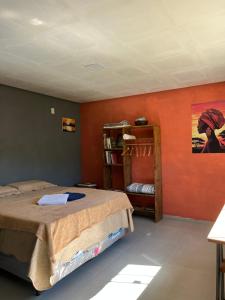 a bedroom with orange walls and a bed and a shelf at Casa Jatobá in Ibicoara