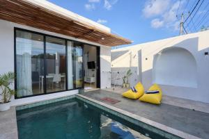 a house with a swimming pool and two yellow cushions at Nalumi Villa in Nusa Penida