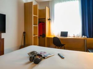a room with a bed with a book and headphones at ibis Genève Petit Lancy in Geneva