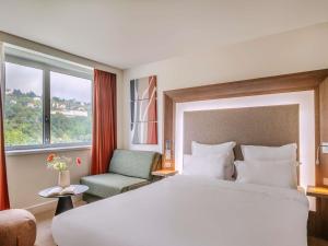 a hotel room with a large bed and a chair at Novotel Lyon Centre-Confluence Bord de Saone in Lyon