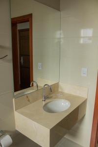a bathroom with a sink and a mirror at Patos Hotel in Patos de Minas