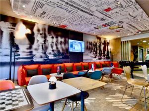 a restaurant with tables and chairs and a large mural at ibis Les Herbiers in Les Herbiers