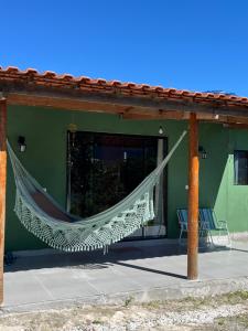 a hammock on the side of a green building at Casa Jatobá in Ibicoara